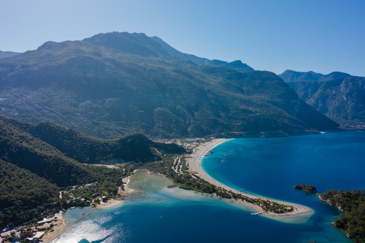 Breathtaking aerial view of a mountainous coastline with turquoise waters and sandy beaches.